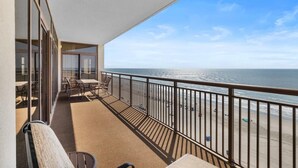 A balcony with a view of the beach, a table, chairs, and a railing. - A Luxurious 5-Bedroom, 4.5-Bathroom Retreat for 14 (North Myrtle Beach)