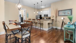 A modern kitchen with a central island, bar stools, and pendant lighting. - Modern 1 Bedroom Luxury Flat Your Stylish Oasis (North Myrtle Beach)