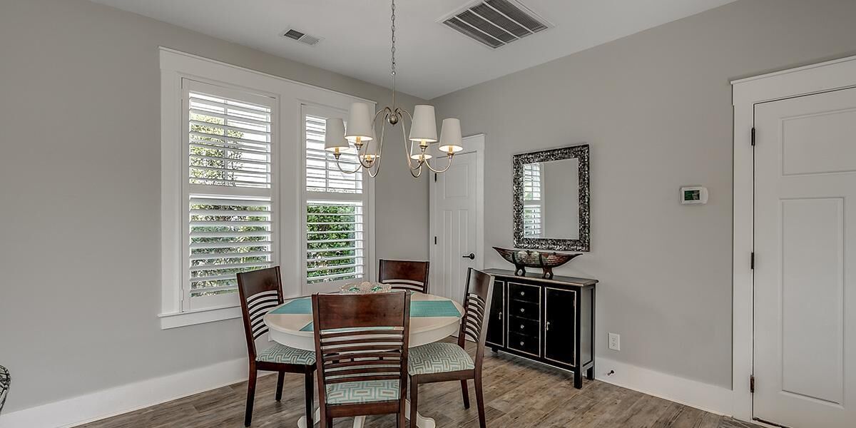 Un coin repas comprenant une table ronde, des chaises, un lustre et un buffet.