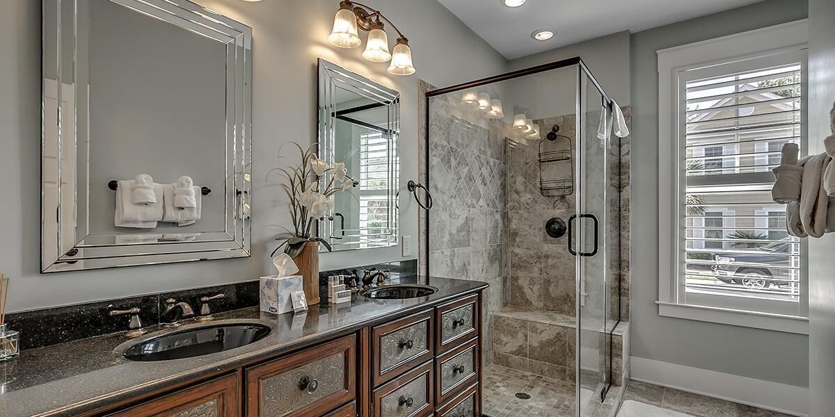 A modern bathroom with a glass-enclosed shower, a double sink vanity, and large mirrors.