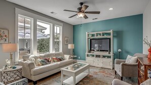 A living room with a sofa, coffee table, TV stand, and ceiling fan. - Elegant 3 Bedroom: Unmatched Comfort for 6 Guests (North Myrtle Beach)