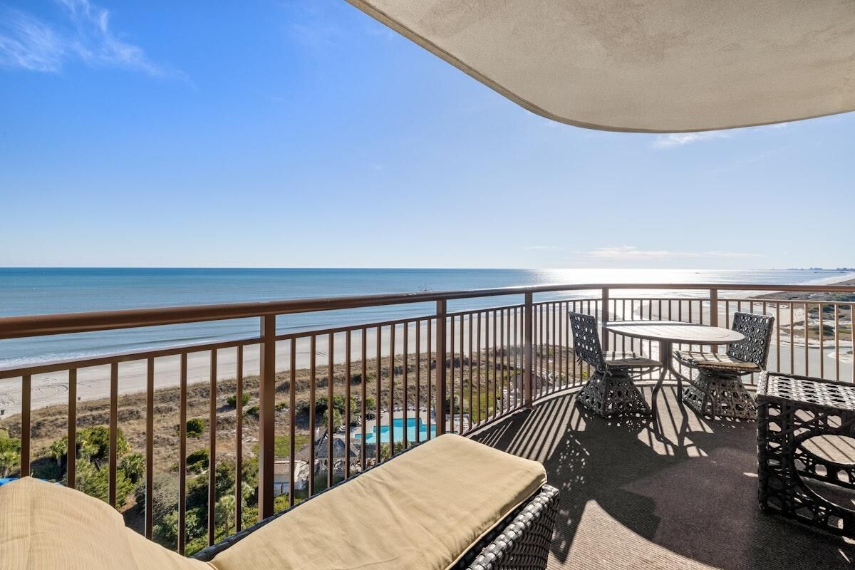 A balcony with a view of the beach and ocean.