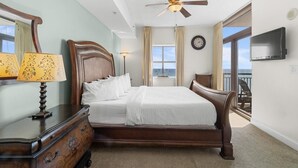 A bedroom with a wooden bed, a ceiling fan, a TV, and a view of the outdoors. - Elegance and Comfort Unite: A Cozy Getaway for 10 (North Myrtle Beach)