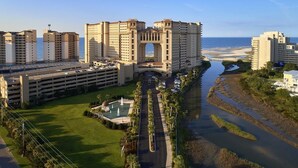 A large hotel with a central archway, multiple parking levels, a swimming pool, and a river. - Elegance and Comfort Unite: A Cozy Getaway for 10 (North Myrtle Beach)