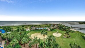 A coastal property with a grassy area, palm trees, a swing set, and a view of the ocean. - Unparalleled Luxury in Our Exquisite 4 Bdrm Condo (North Myrtle Beach)