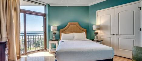 Un dormitorio con una cama grande, un ventilador de techo y vistas a través de un ventanal corredera.