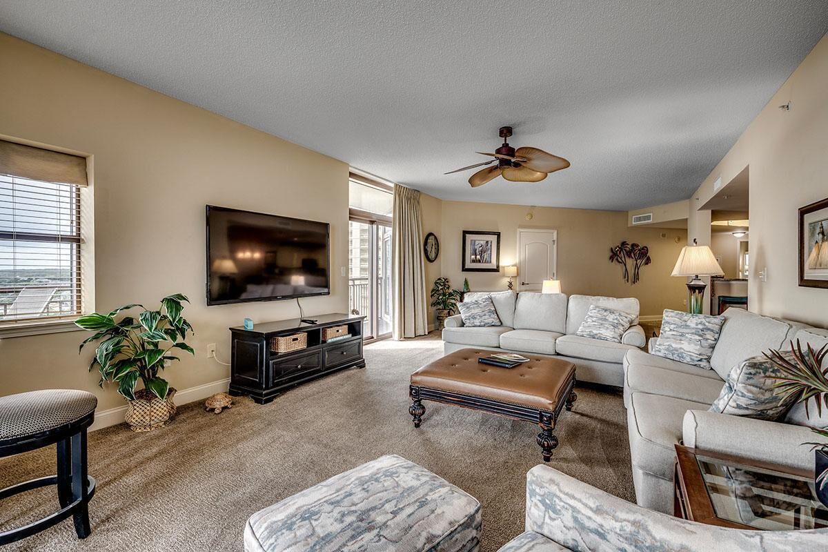 A living room with a television, sofas, a coffee table, and a ceiling fan.