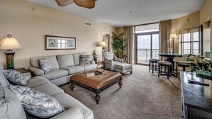 A spacious living room with a sofa, armchairs, a coffee table, and a dining area. - Seaside Splendor: 4 Bedroom Oceanfront Condo (North Myrtle Beach)