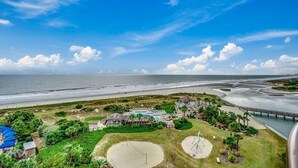 A coastal hotel with a beach view, a large pool, and a pier extending into the water. - Seaside Splendor: 4 Bedroom Oceanfront Condo (North Myrtle Beach)