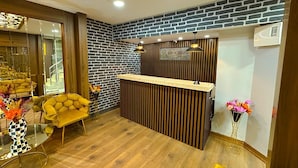 A reception area with a wooden reception desk, a black and white brick wall, and a yellow sofa.