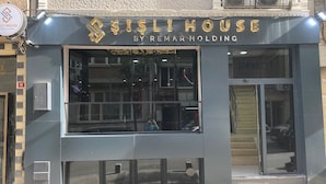 A modern building with a large glass window and a sign that reads "SISLI HOUSE BY REMAR HOLDING".