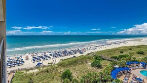 A beach resort with a pool area, beach umbrellas, and a view of the ocean. - Indigo Tower: Luxurious Oceanfront 4 Bdrm Paradise (North Myrtle Beach)