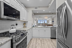 Une cuisine moderne avec des armoires blanches, des appareils en acier inoxydable et un plancher en bois.