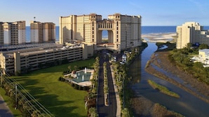 A large hotel with a central archway, multiple parking levels, a swimming pool, and a river. - Unwind & Relax 3 Bedroom Home Near the Beach (North Myrtle Beach)