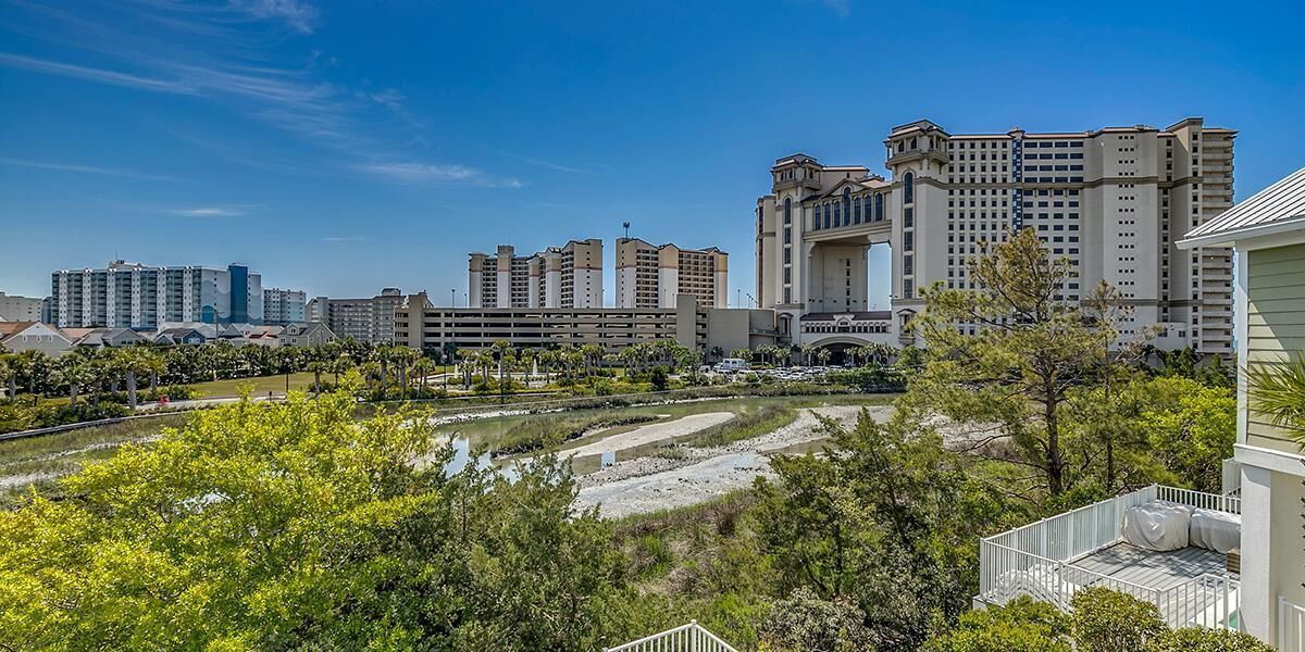 A hotel complex with multiple high-rise buildings, a landscaped garden area, and a clear sky.