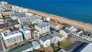 Ett flygbildsbild av ett bostadsområde vid kusten med byggnader, en strand och en parkeringsplats.