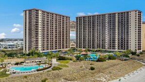 A high-rise hotel with multiple balconies, a pool area, and a beach view.
