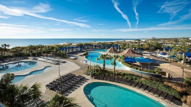 A resort with multiple swimming pools, lounge areas, and a view of the ocean.
