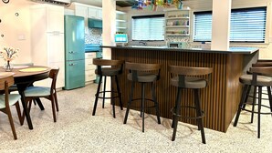 A modern kitchen with a bar area, white cabinetry, and a speckled floor. - Orlando Vacation Rental Heated Pool & Spa 5 BR 3 BA Near Space, Nature, Disney  (Titusville)
