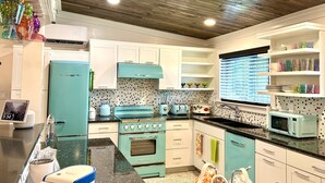 A kitchen with white cabinets, a teal stove, and a microwave. - Orlando Vacation Rental Heated Pool & Spa 5 BR 3 BA Near Space, Nature, Disney  (Titusville)