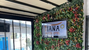 A hotel entrance with a sign reading "Tiana Boutique Hotel" and a decorative wall of foliage and flowers. - Tiana Butik Otel (Bodrum)