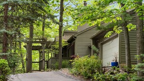 A house with a covered porch, surrounded by dense forest.
