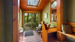 A cozy wooden cabin with a large skylight, a rocking chair, and a bench.