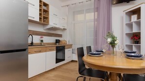 Una cocina moderna con refrigerador de acero inoxidable, armarios de madera, horno empotrado y una mesa de comedor con sillas.