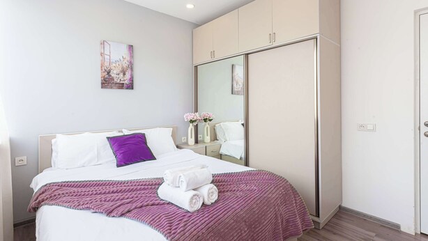 Une chambre d’hôtel moderne avec un grand lit, une armoire, un miroir et un tableau au mur.