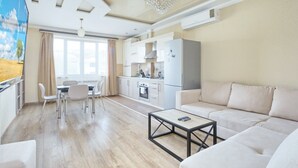 Un salon moderne comprenant un canapé, une table basse et un coin repas avec des chaises.