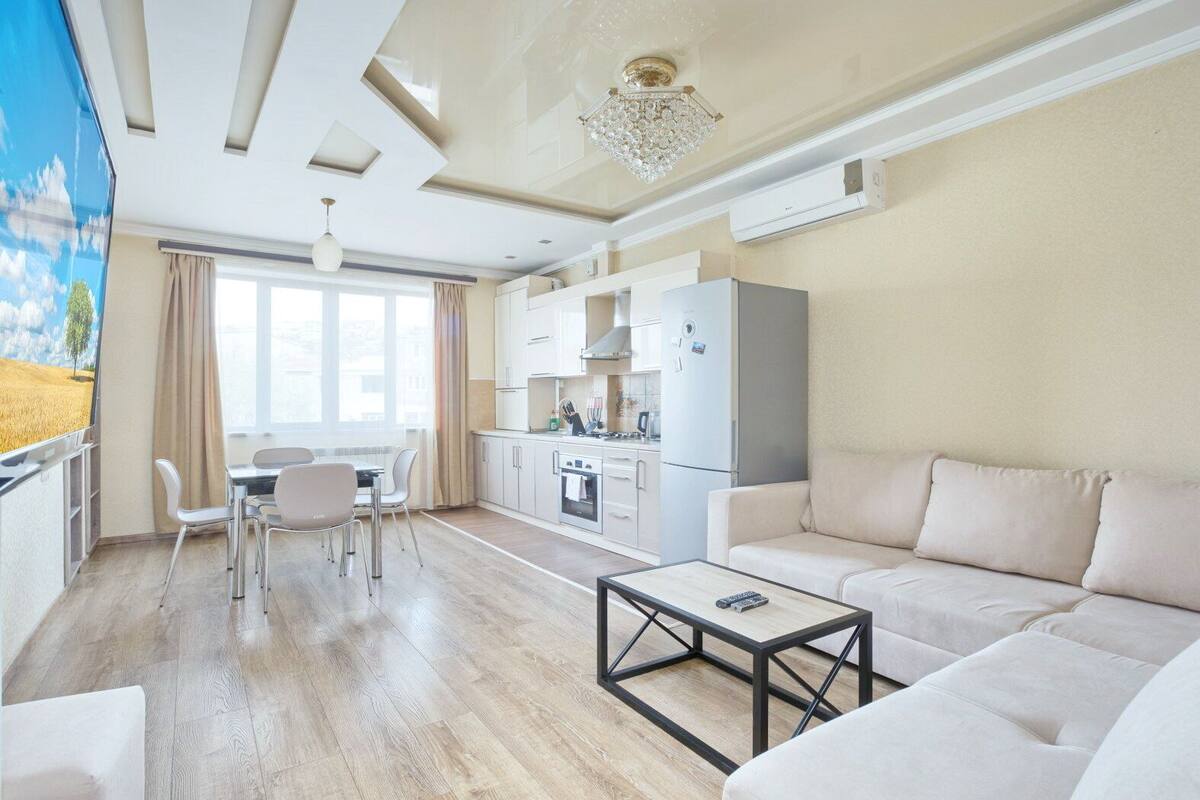 A modern living room with a sofa, a coffee table, and a dining area with chairs.