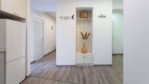 Un couloir avec un comptoir d’accueil, un panneau d’affichage indiquant « Bienvenue » et un porte-manteau.