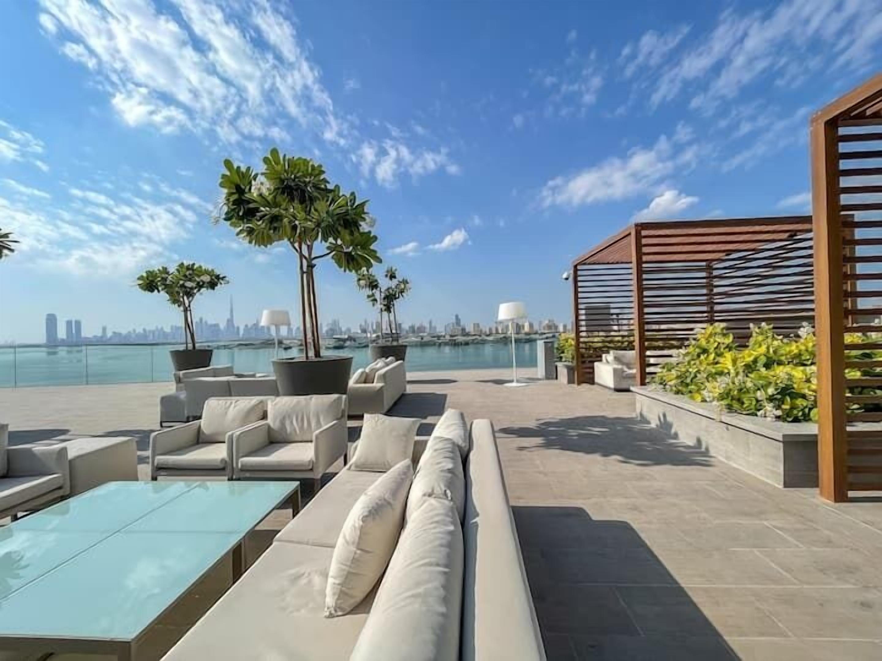 Une terrasse sur le toit, aménagée avec des espaces de détente en plein air, des plantes en pot et offrant une vue sur le panorama urbain.