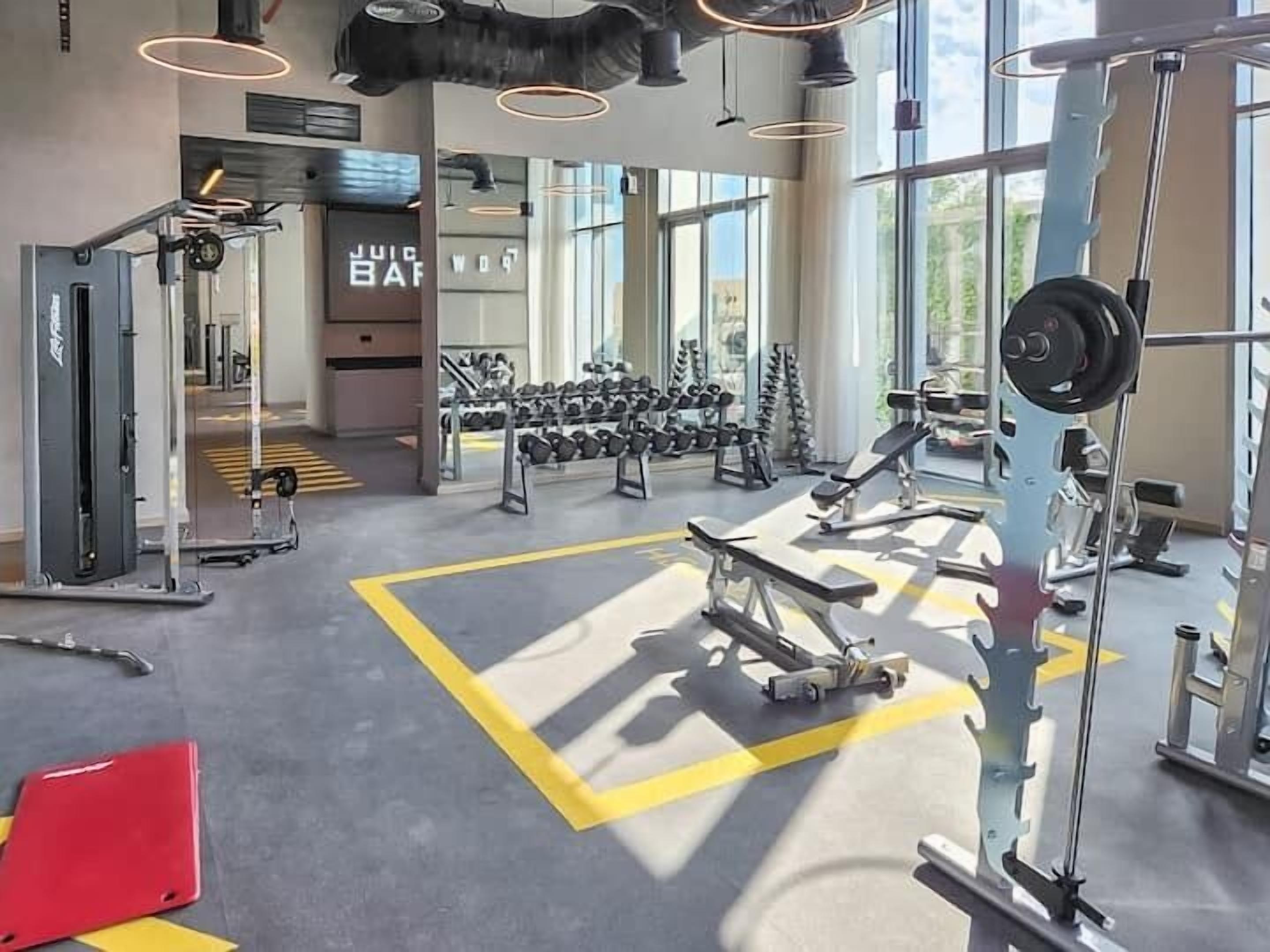 Ein Fitnessstudio mit unterschiedlichen Trainingsgeräten, darunter Kurzhanteln, Bänke und Kraftgeräte.