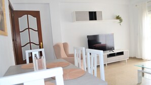 Un salon moderne avec une table à manger, des chaises, un téléviseur et une décoration minimaliste.