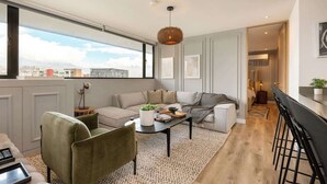 Un salón moderno con sofá, una mesita de centro y vista a la ciudad.