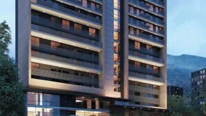 Un hotel moderno con varios balcones, un logotipo destacado en la parte superior y vistas del paisaje circundante.