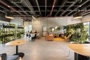 Un espace intérieur moderne, aménagé avec des tables, des chaises et des plantes.