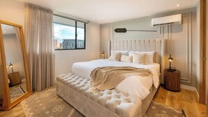 Un dormitorio con una cama grande, un espejo, una ventana y un equipo de aire acondicionado.