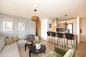 Un salon moderne avec un canapé, une table basse et un coin repas équipé de tabourets de bar.
