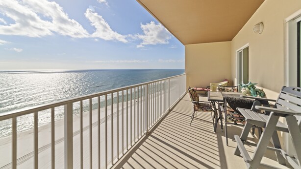 Un balcon avec vue sur l’océan, une balustrade blanche et du mobilier d’extérieur.