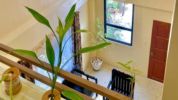 Ein mehrgeschossiges Interieur mit einem Chandelier, Topfpflanzen und Blick ins Freie.