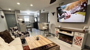 A modern living room with a sofa, a coffee table, a TV, and a fireplace.