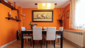 A dining area with a table, chairs, a painting, and a radiator.