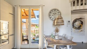 Eine Küche mit Holztisch und Stühlen, einer Uhr und Blick durch eine Glastür.