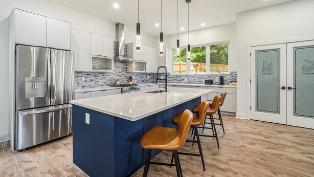 Una cocina moderna con una isla central, electrodomésticos de acero inoxidable y una pared decorada en azul.