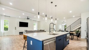 Una cocina moderna con una isla central, electrodomésticos de acero inoxidable e iluminación colgante.