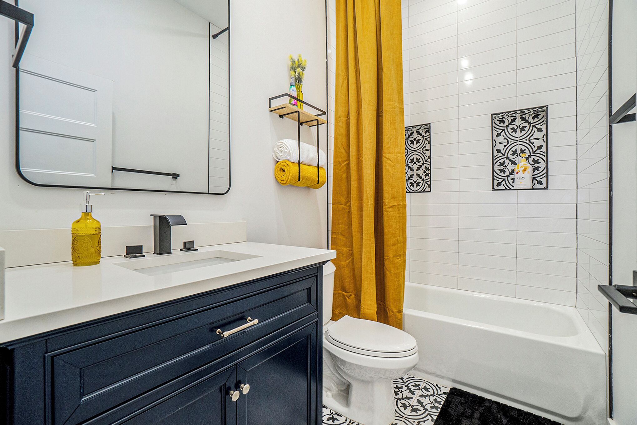 A modern bathroom with a white sink, black cabinet, and a white toilet.