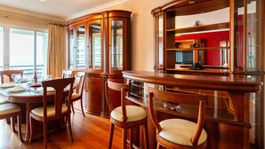 Un comedor con mesa y sillas de madera, un mueble empotrado con puertas de vidrio y vistas al exterior a través de amplias ventanas.