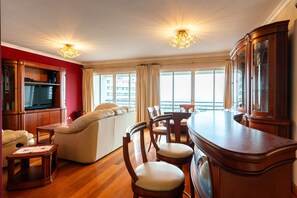 A spacious living room with a sofa, chairs, a wooden coffee table, and a TV. - Katerina´s Place, 3 Bedrooms Near Praia Formosa, Restaurants and Shops (Funchal)